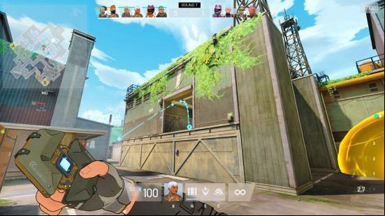 Spectre Divide preview: a first-person screenshot of someone about to throw a small device up into an open window. A blue arc shows the trajectoryo